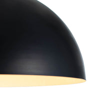 Close-up of a sleek, black metal dome pendant light with a warm glow.