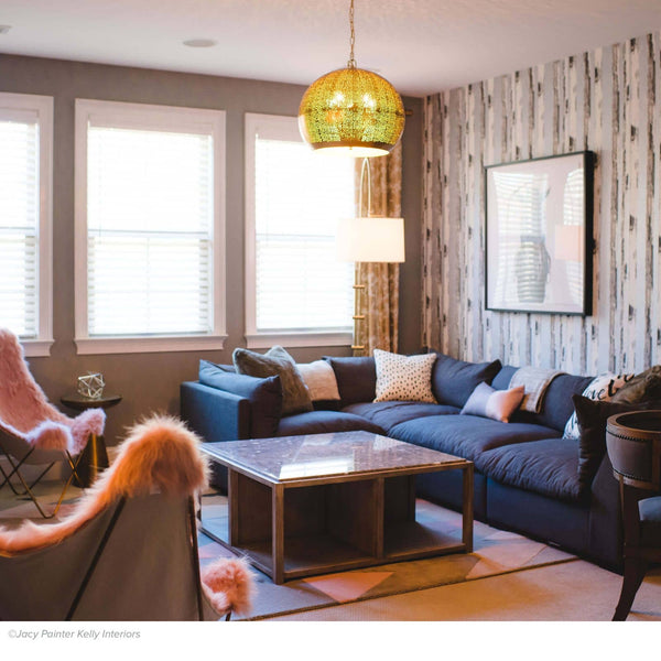 Pierced natural brass sphere pendant light with organic perforated design illuminates a modern living room.