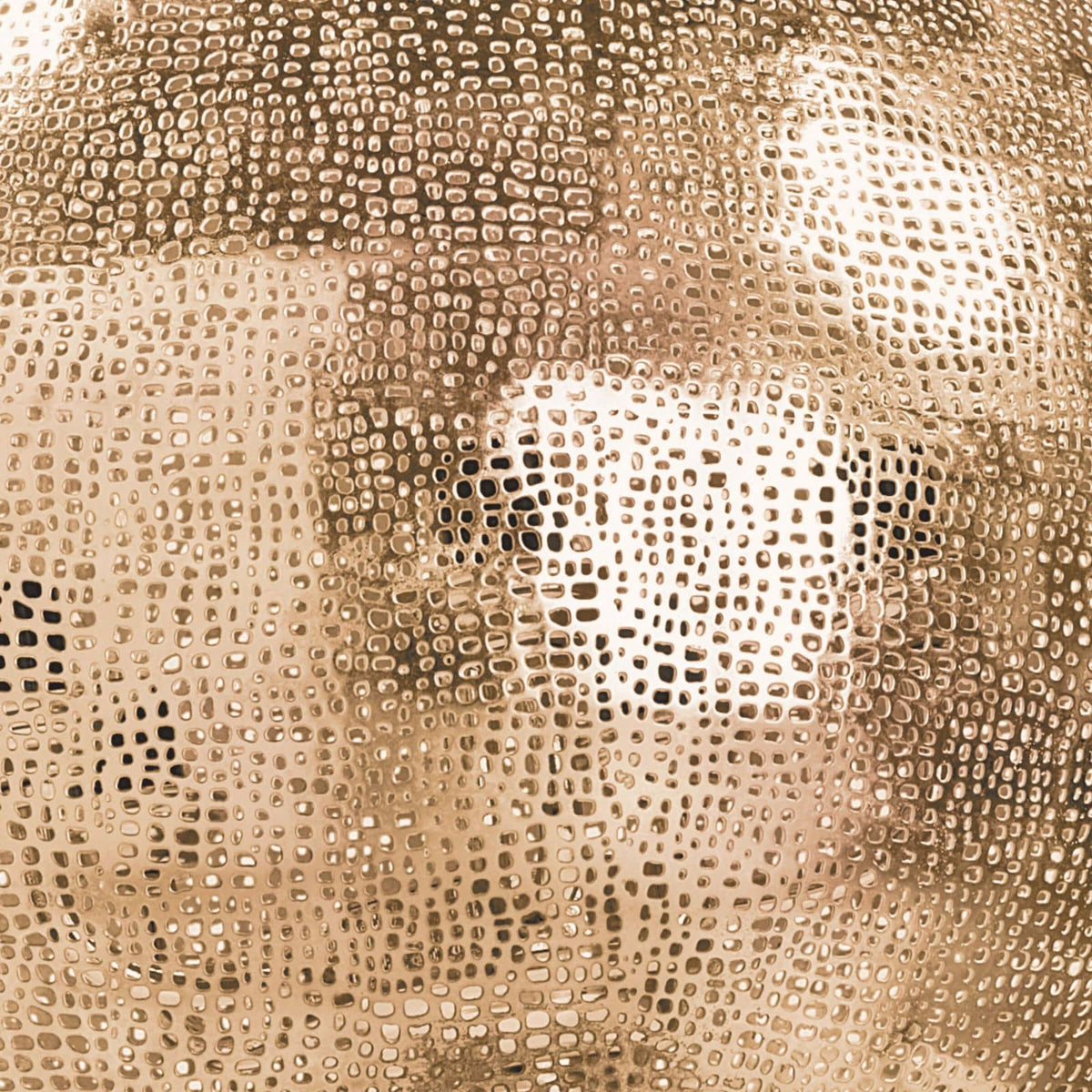 Close-up of a natural brass pierced metal sphere pendant with an organic perforated design.