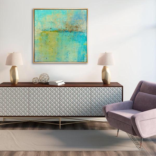 Abstract giclee canvas painting by Maeve Harris in turquoise and gold, framed above a textured white console.