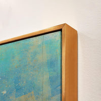 Close-up of a giclee canvas painting with textured blue and gold abstract art in a gold frame.