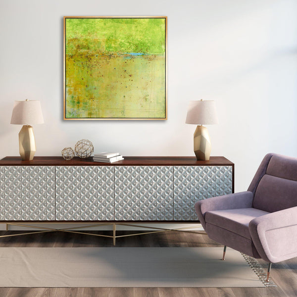 Abstract green and yellow giclee canvas painting in a gold frame above a modern console.