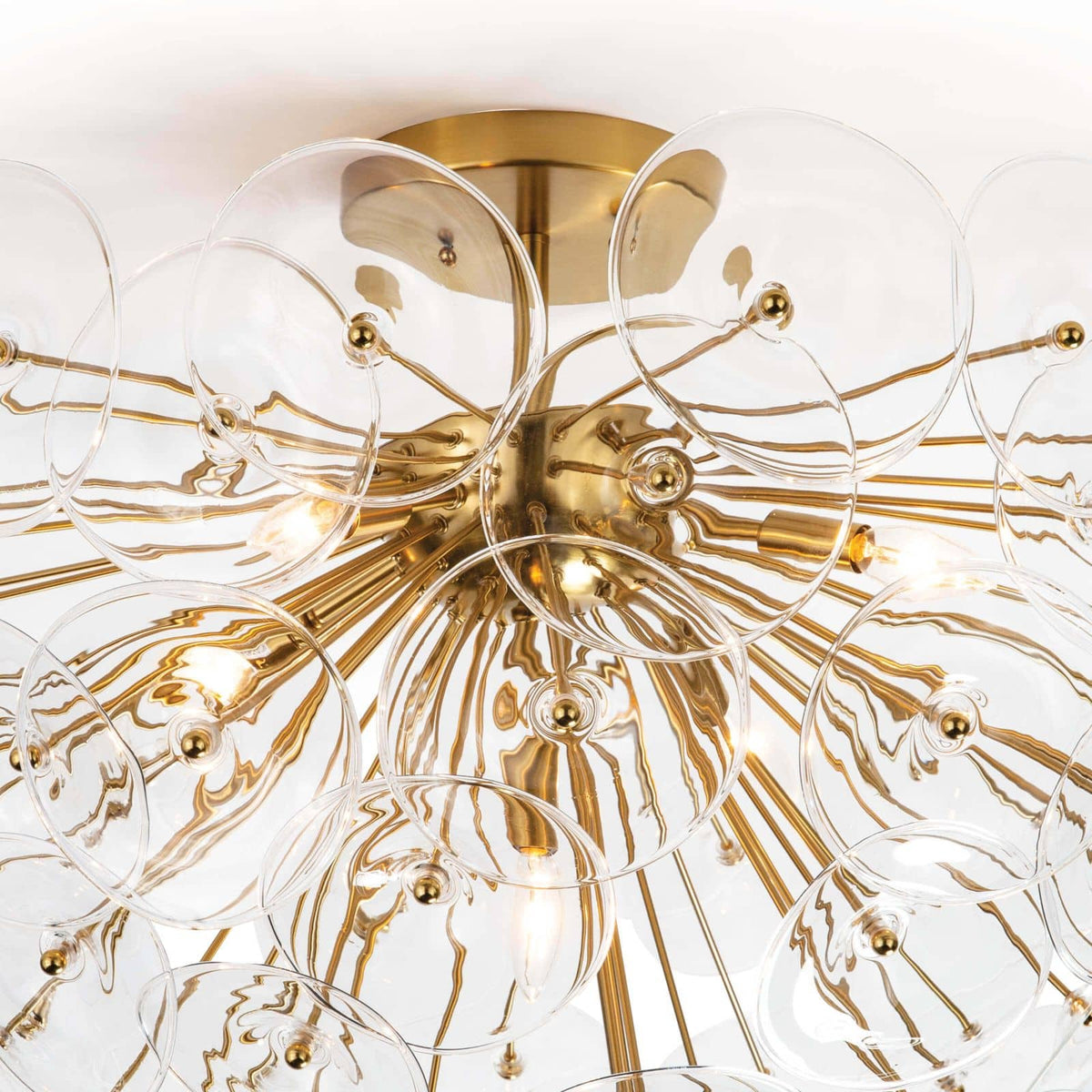 Poppy semi-flush mount light with natural brass rods and undulating clear glass discs.