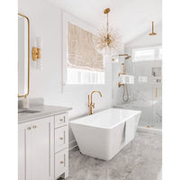 Poppy sputnik-style orb chandelier with clear glass discs and natural brass rods in a modern white bathroom.