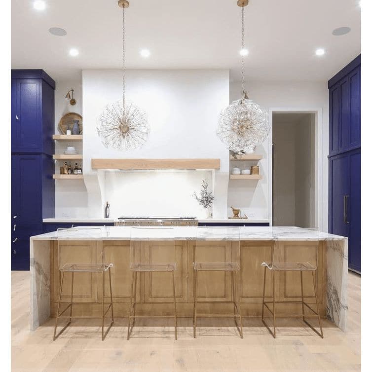 Two Poppy sputnik-style orb chandeliers with clear glass discs and natural brass rods in a modern kitchen.