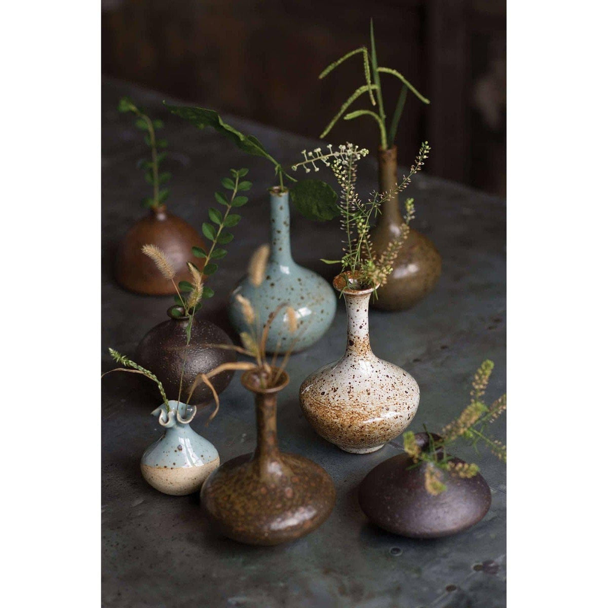 Eclectic set of 8 handmade porcelain bud vases in varying shapes, sizes, and colors, from blue to brown.