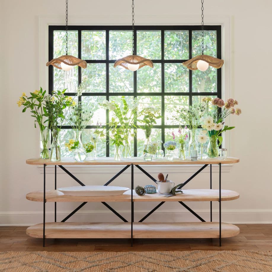 Three Provence Cafe Pendants with twisted rope shades and white glass globes hang above a console table with flowers.