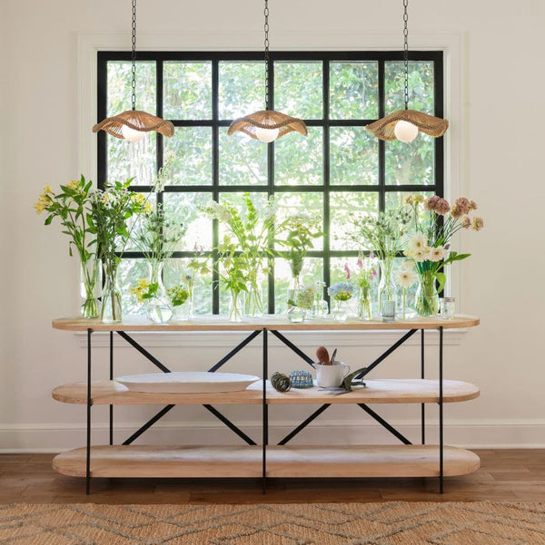 Three Provence Cafe Pendants with twisted rope shades and white glass globes hang above a console table with flowers.