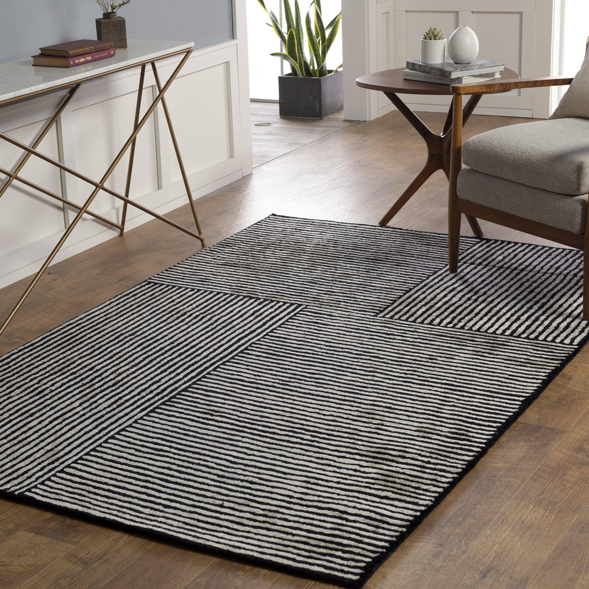 Black and white hand-tufted viscose rug with a modern striped geometric pattern on a wooden floor.