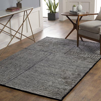 Black and white hand-tufted viscose rug with a modern striped geometric pattern on a wooden floor.