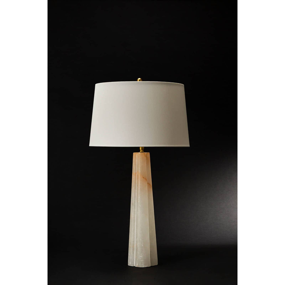 Large alabaster table lamp with a tapered base and a white linen drum shade.