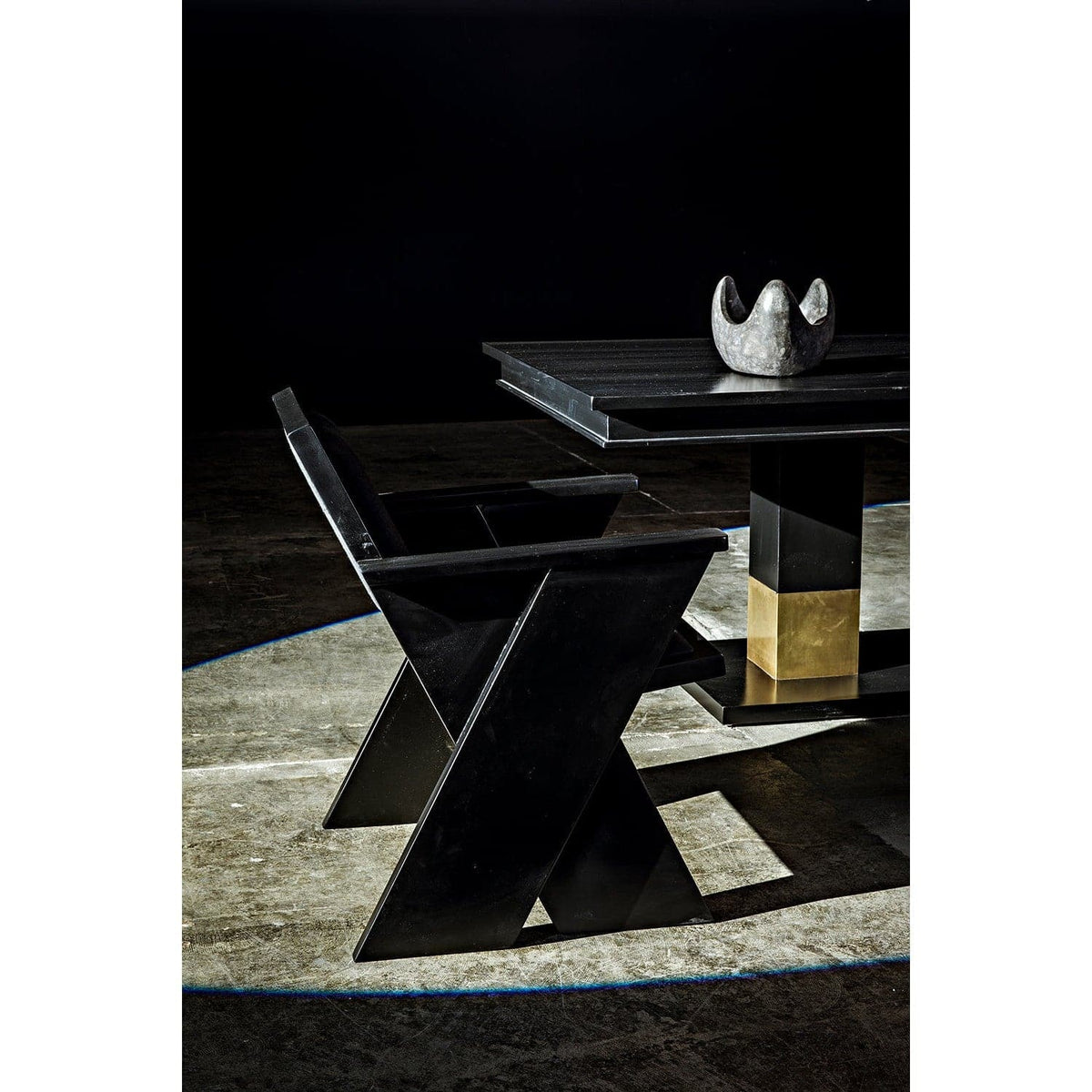 Black mahogany dining table with rectangular lines and brass leg bands, next to a matching chair.