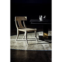 Ravenko black mahogany dining table with brass leg bands, next to a light-colored chair.