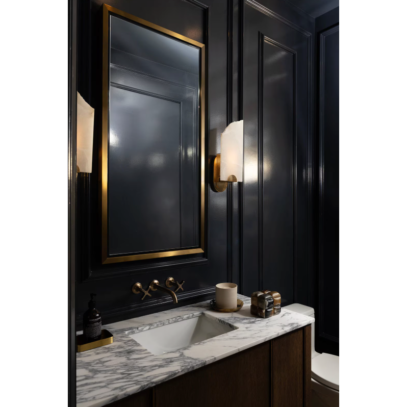 Rectangle natural brass mirror with a subtle frame, mounted above a marble vanity with a sink and brass fixtures.