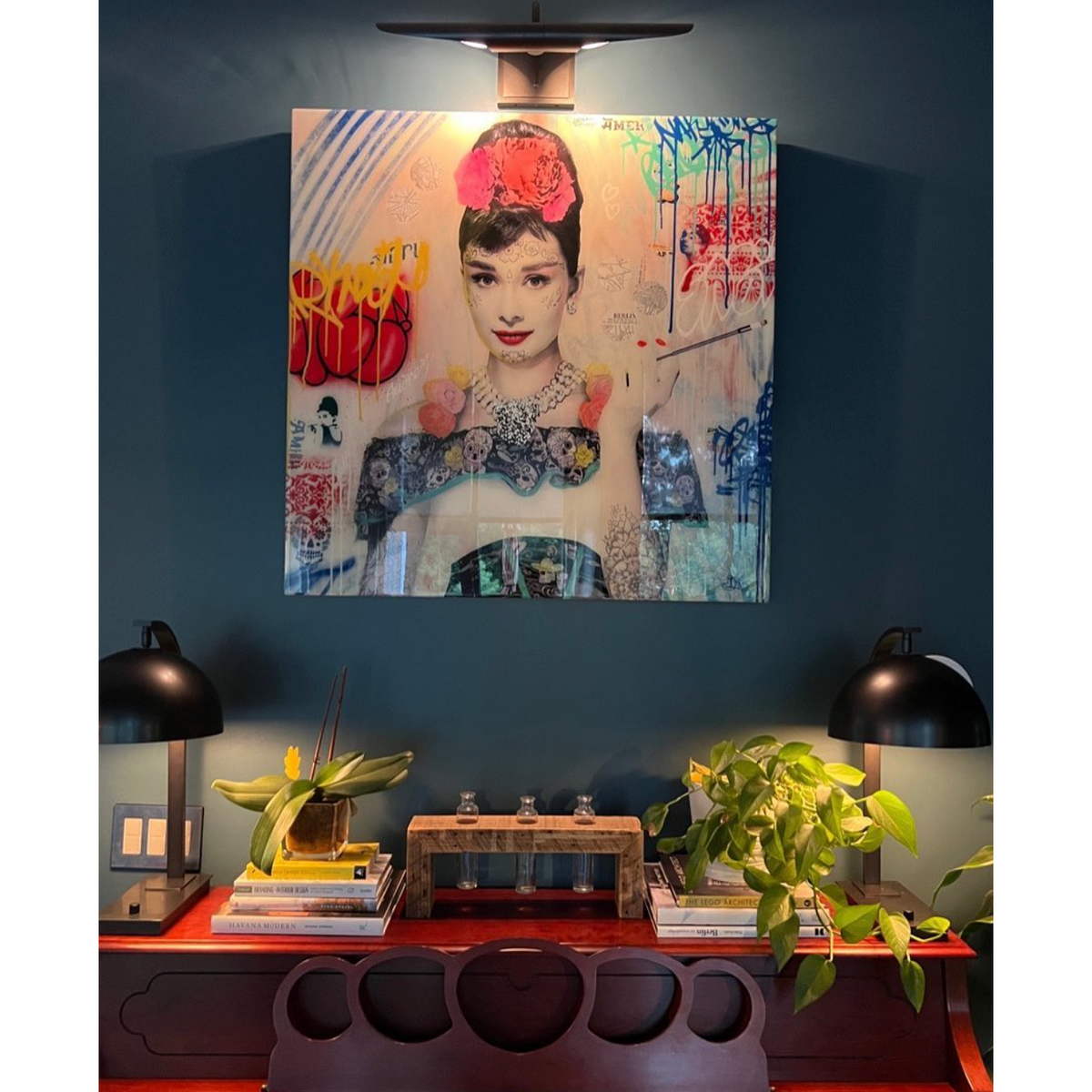 Large oil-rubbed bronze Redford picture light illuminating a colorful Audrey Hepburn artwork above a desk.