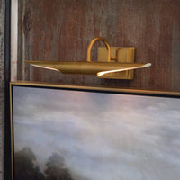 Redford Small Natural Brass Picture Light illuminating artwork, featuring a classic museum-inspired design.