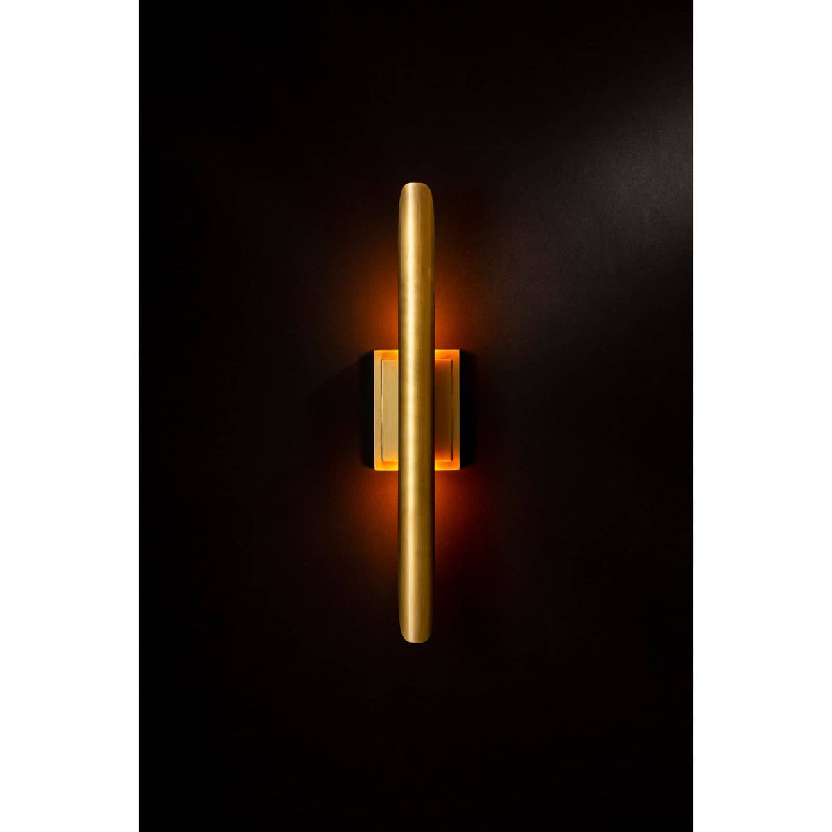 Redford Sconce in natural brass, a modern 22" tall steel wall light with warm glow.