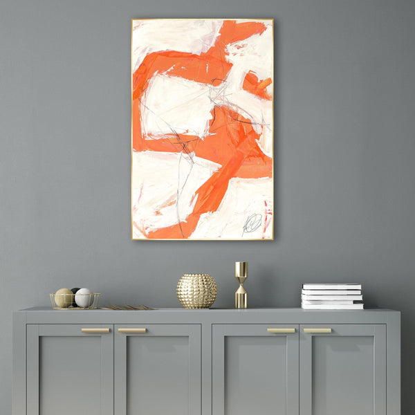 Abstract Reef I giclee canvas painting with orange and white brushstrokes, framed in gold, above a gray cabinet.
