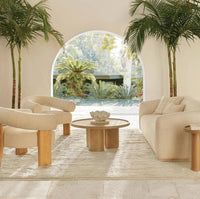Large creamy white ruffle ceramic bowl on a wooden coffee table in a bright living room.
