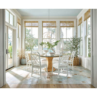 White Sail Chandelier above a round glass dining table with white chairs in a bright room.