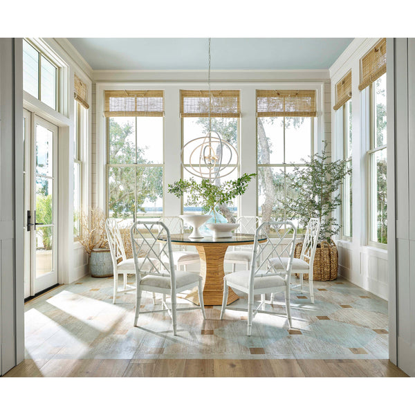 White Sail Chandelier above a round glass dining table with white chairs in a bright room.