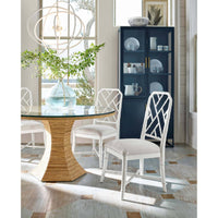 White Sail Chandelier with airy silhouette over a round glass table with a rattan base.