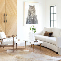 Two Sanya small white metal vases with a paper maché-inspired finish on a marble coffee table in a modern living room.