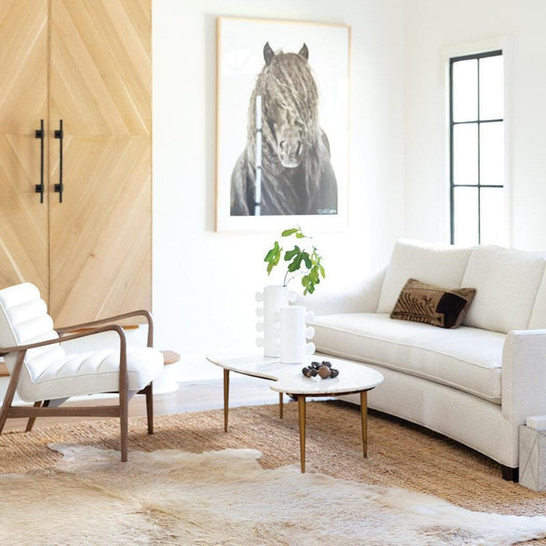 Two Sanya small white metal vases with a paper maché-inspired finish on a marble coffee table in a modern living room.