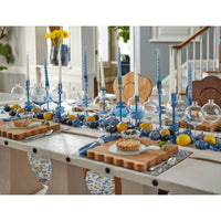Elegant sapphire glass candlesticks with blue and white taper candles on a decorated dining table.