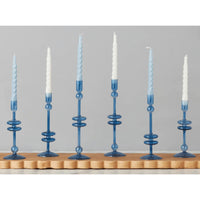Six elegant sapphire blue glass candlesticks with white and blue spiral taper candles.
