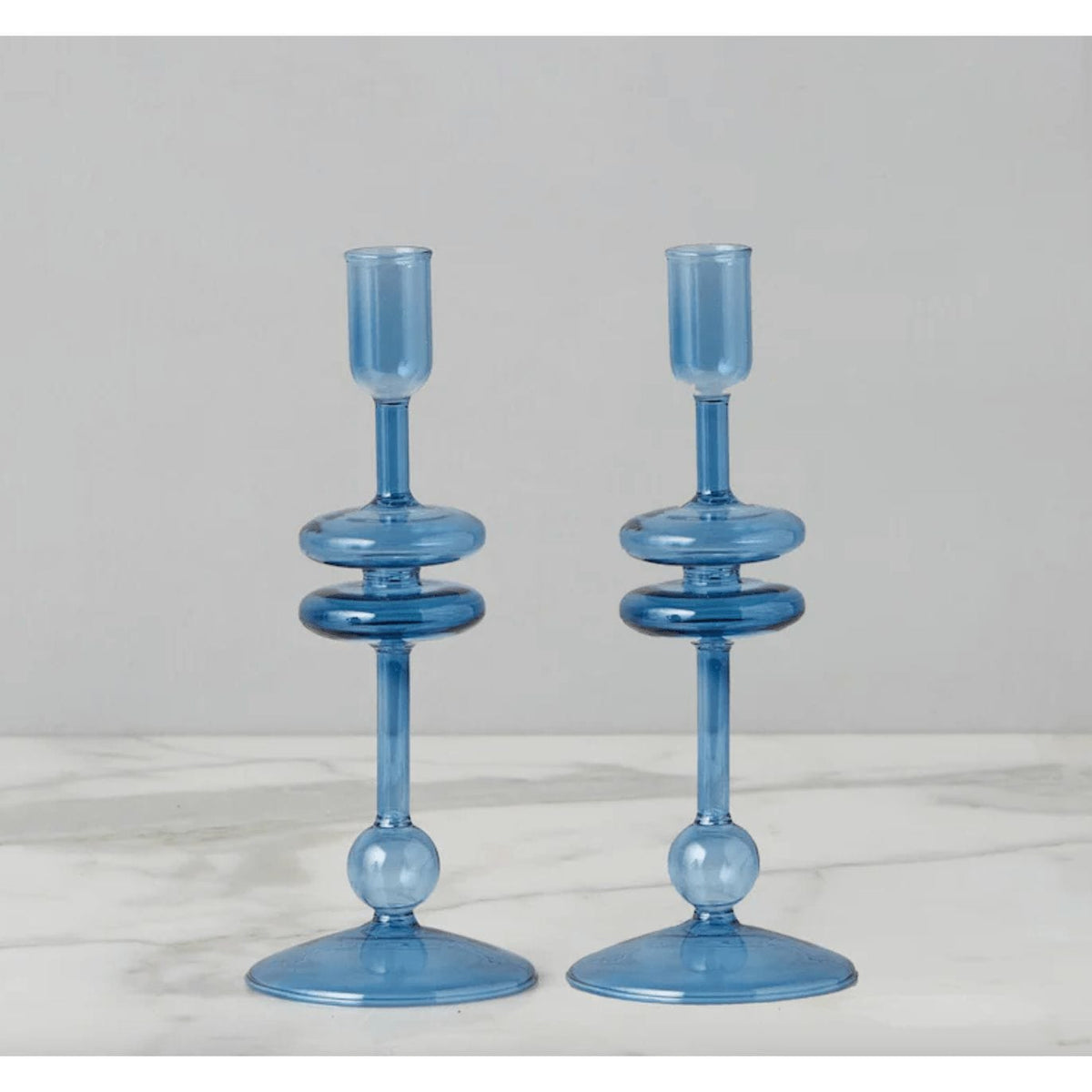 Pair of elegant 9"H sapphire blue glass candlesticks with stacked ring design on a marble surface.