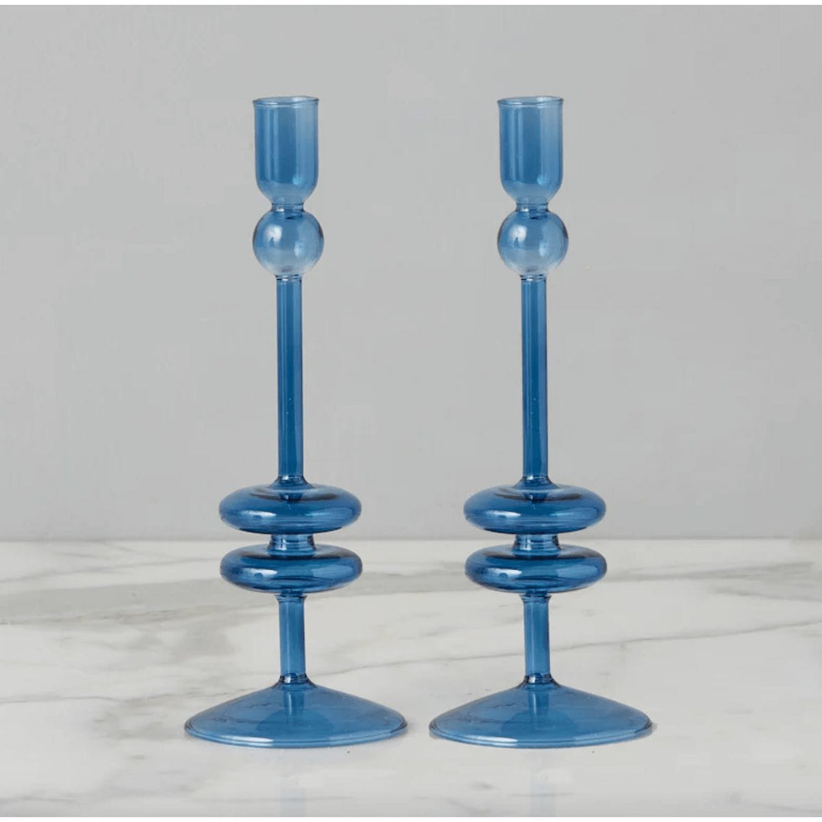 Pair of elegant sapphire blue glass candlesticks with unique stacked ring and sphere design.