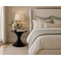 Schilling round side table with hand-rubbed black finish and concentric ring design in a bedroom.