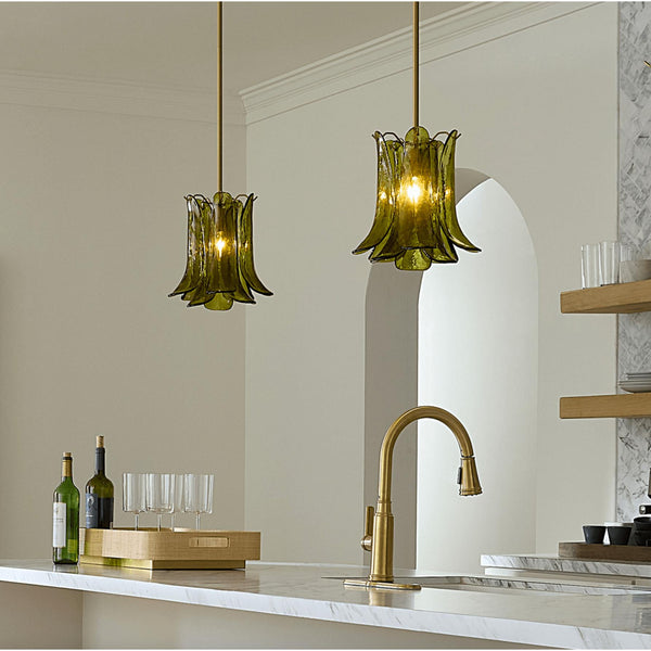 Green pendant lights hanging above a kitchen counter with a gold faucet.