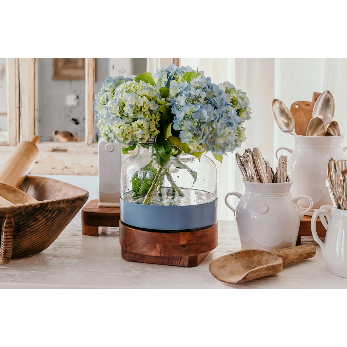Decorative items including a vase with flowers, wooden bowls, and kitchen utensils on a table.