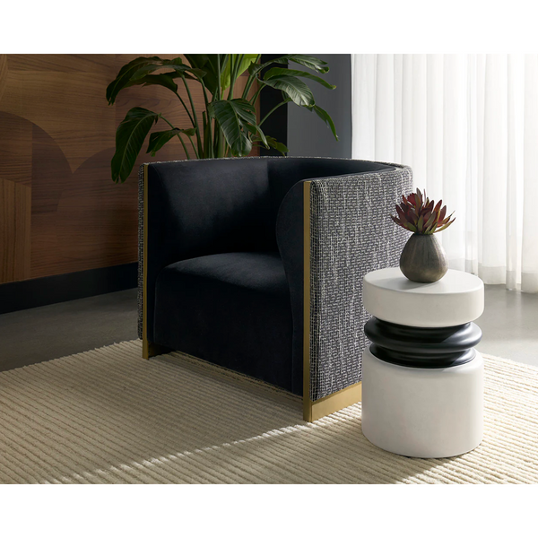 Modern armchair with a white side table and plant in a room with wooden floor and white curtains.