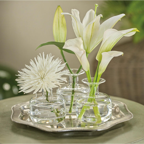 Three small glass vases with white flowers on a silver tray.