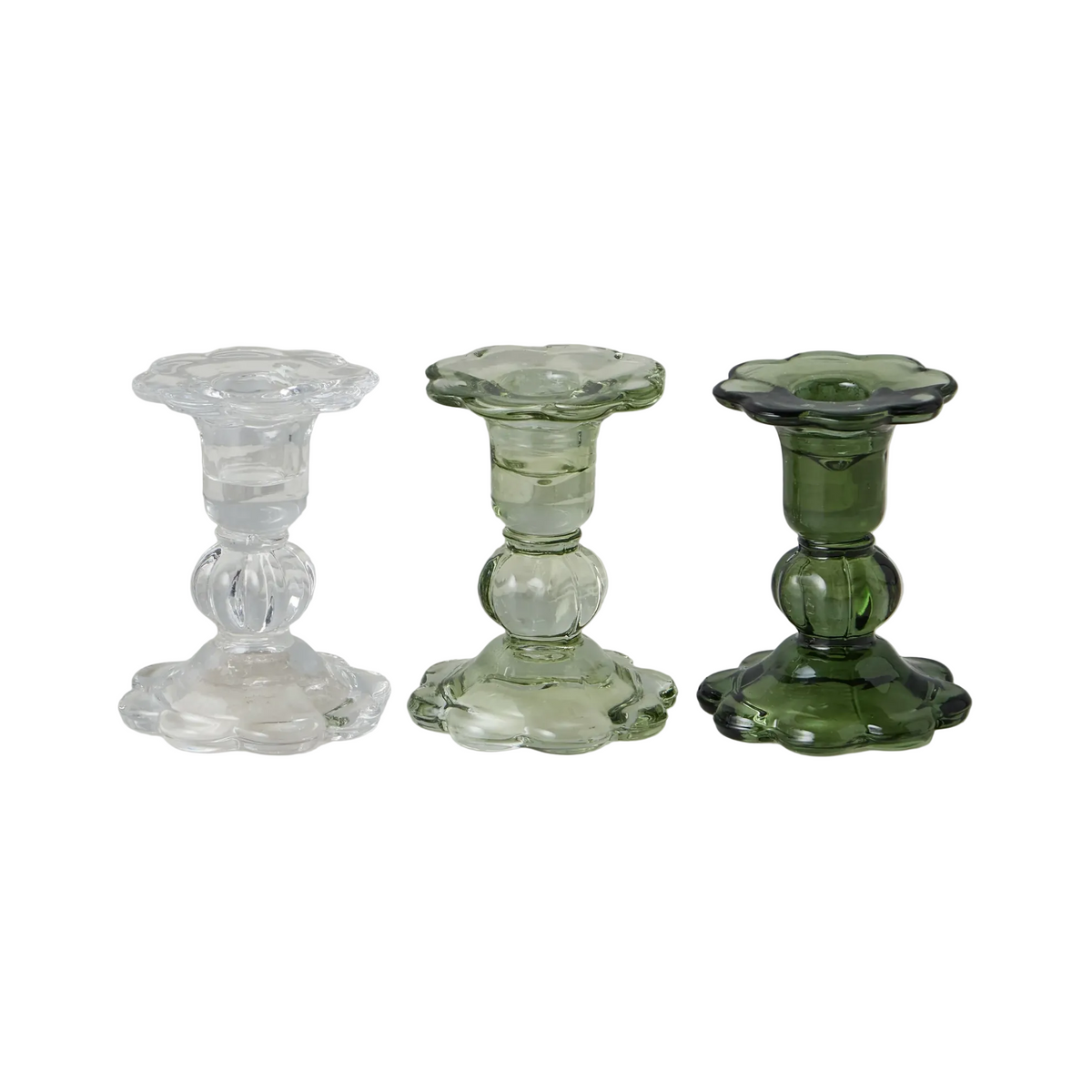Three glass candle holders in clear, green, and a mix of both on a marble surface.