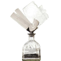 Clear glass bottle with a selenite geode, slabs, and sticks, creating a unique, organic decorative piece.