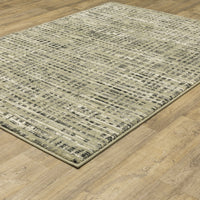 Seneca Beige & Grey Casual Rug with abstract black, ivory, and green lines on a light wood floor.