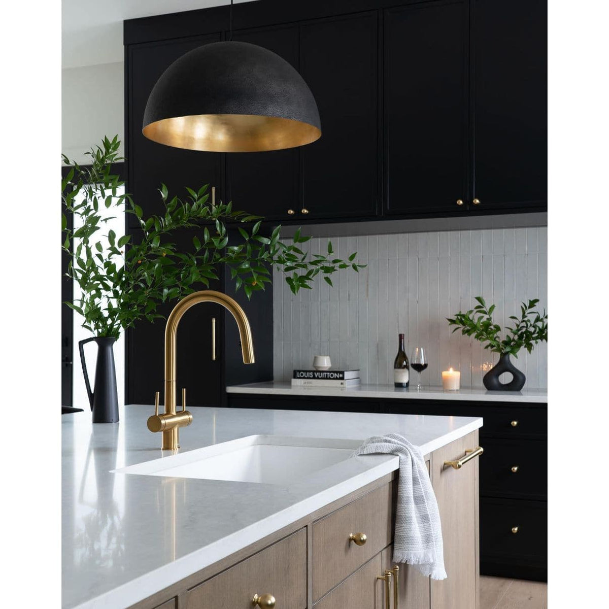 Sigmund Small Black Gold pendant light with a dome shade and gold-leafed interior, hanging over a kitchen island.