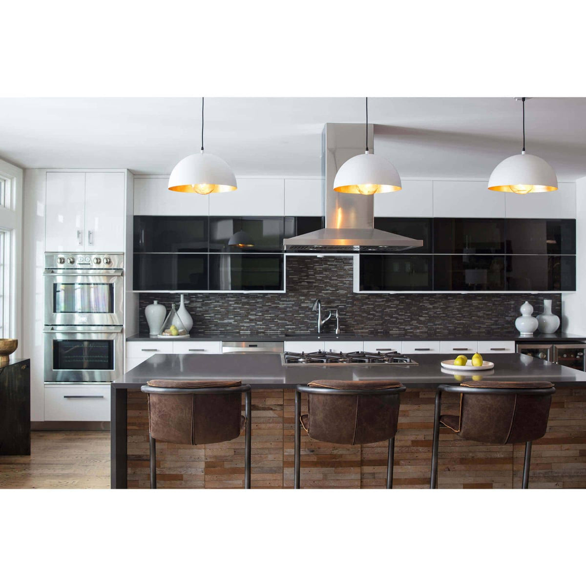 White gold Sigmund pendant lights with gold-leafed interiors illuminating a modern kitchen island.