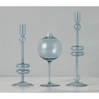 Sky blue glass wine glass vase with sphere top, flanked by two matching candlestick holders.