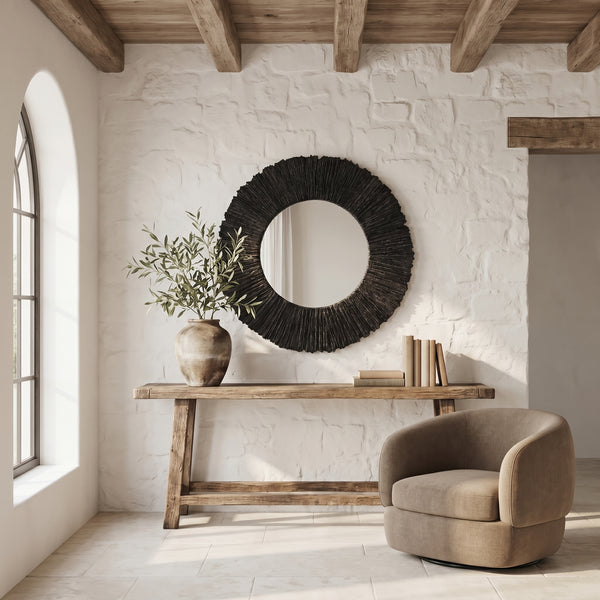Large round slate black mirror with textured frame above a rustic wooden console table.