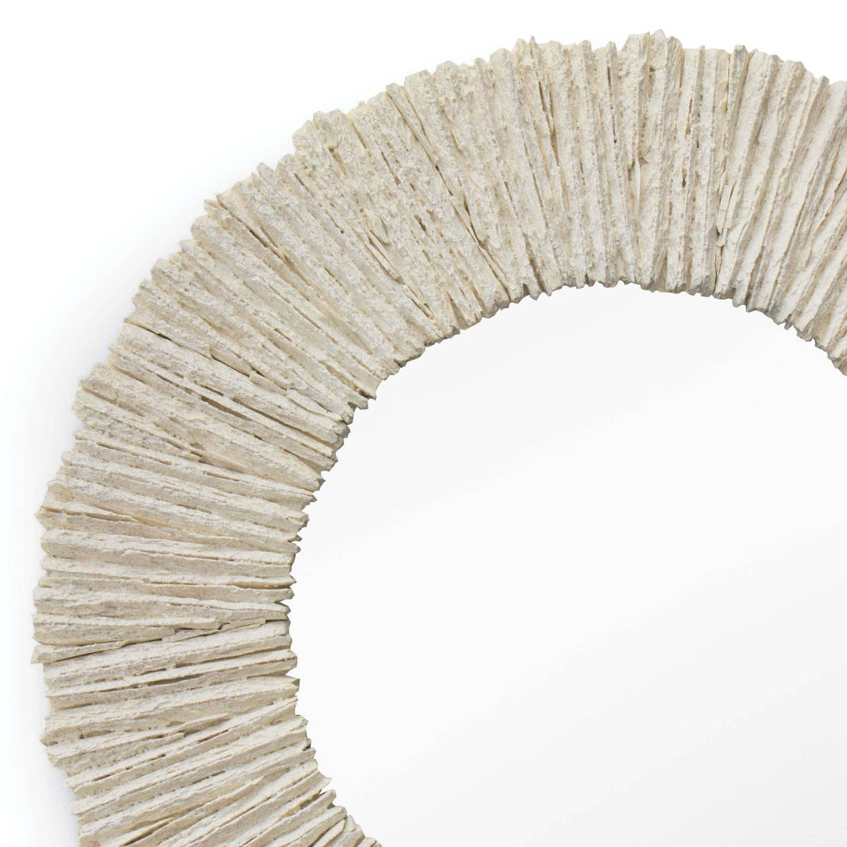 Close-up of a round mirror with a textured, natural slate-inspired frame in a light, rugged finish.
