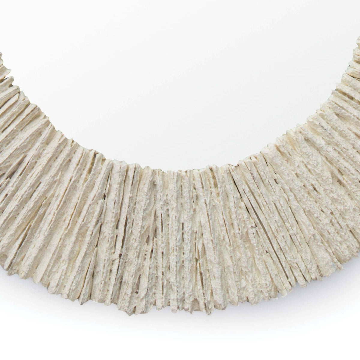 Close-up of a round mirror with a textured, natural slate-like frame in a light, neutral color.