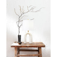Slinkly Marble Table Lamp with white linen shade and arching marble base on a rustic wooden table.
