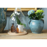 Antique blue French clay pot with handles, holding hydrangeas, on a wooden surface.