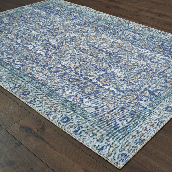 Sofia Blue Casual Rug: Machine-woven polyester chenille rug with antique-inspired floral patterns and a blanket stitch border on a dark wood floor.
