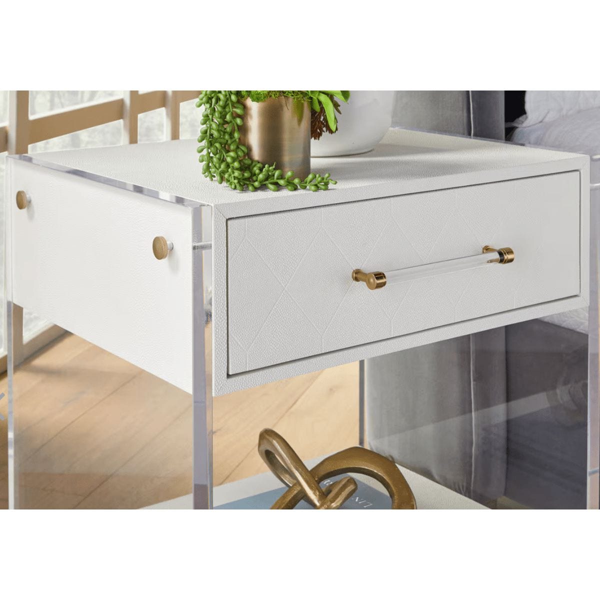 Sonia Pearl Shagreen & Lucite 1-Drawer Nightstand with gold hardware and a plant on top.